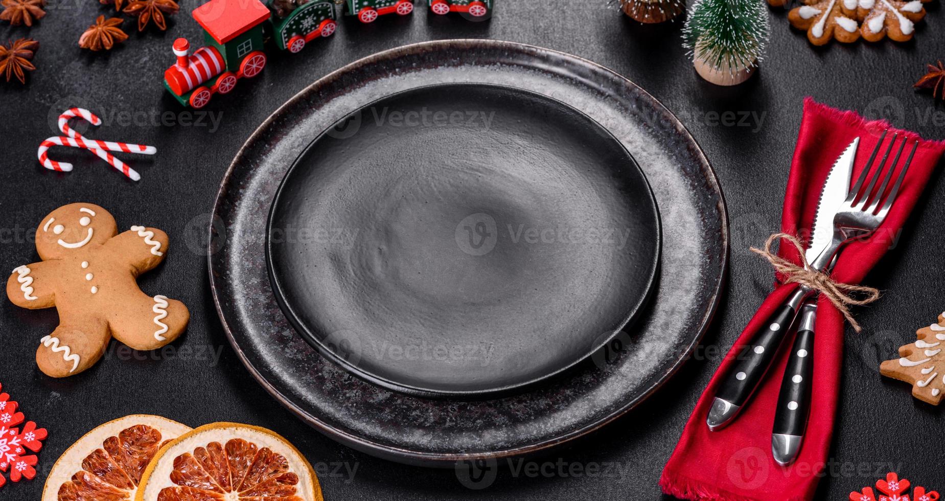Christmas table setting with empty black ceramic plate, fir tree and black accessories photo