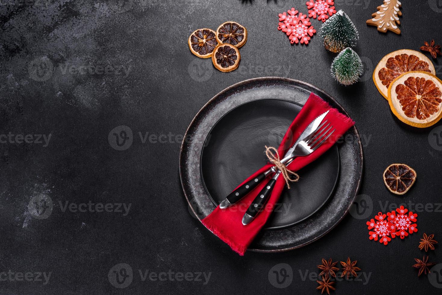 Christmas table setting with empty black ceramic plate, fir tree and black accessories photo