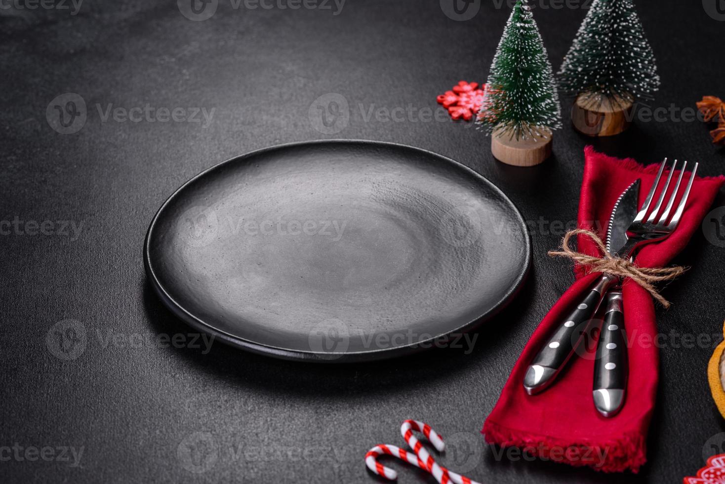 Christmas table setting with empty black ceramic plate, fir tree and black accessories photo