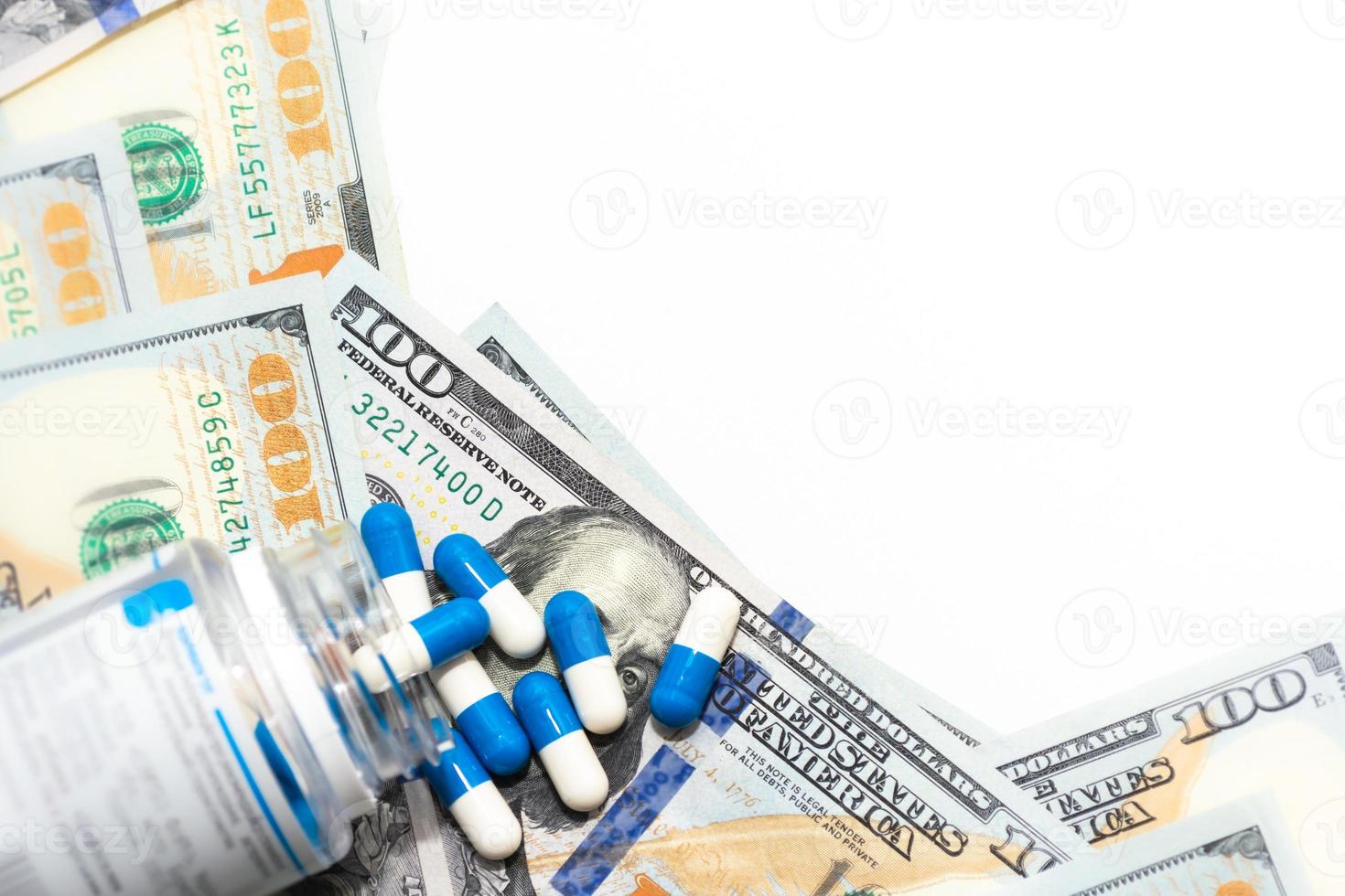 Tablets scattered on 100 dollar bills with a white background for writing. photo