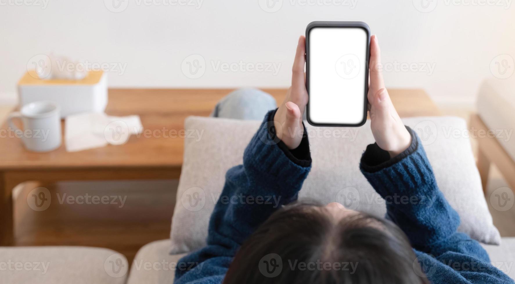 Woman configuring privacy settings on the mobile phone, lying down at home. white screen. Privacy settings appears on the screen. photo