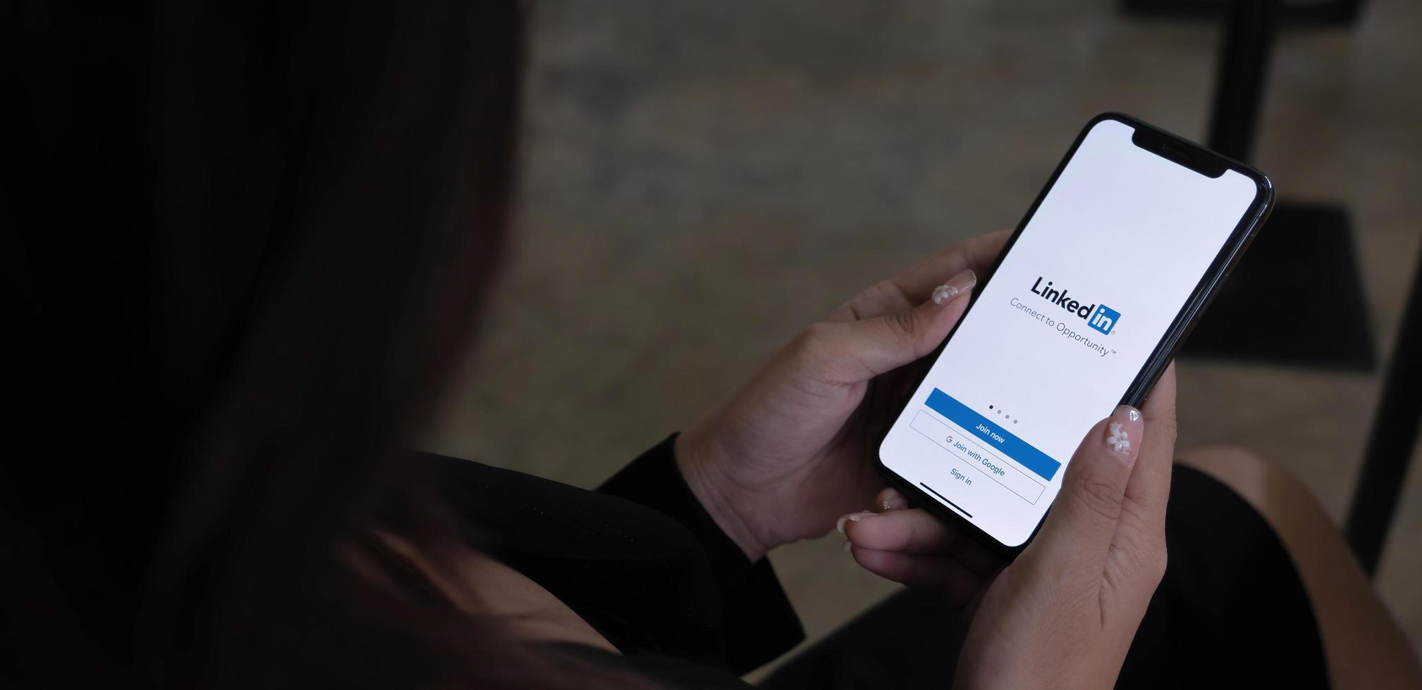A women holds Apple iPhone Xs with LinkedIn application on the screen.LinkedIn is a photo-sharing app for smartphones. photo