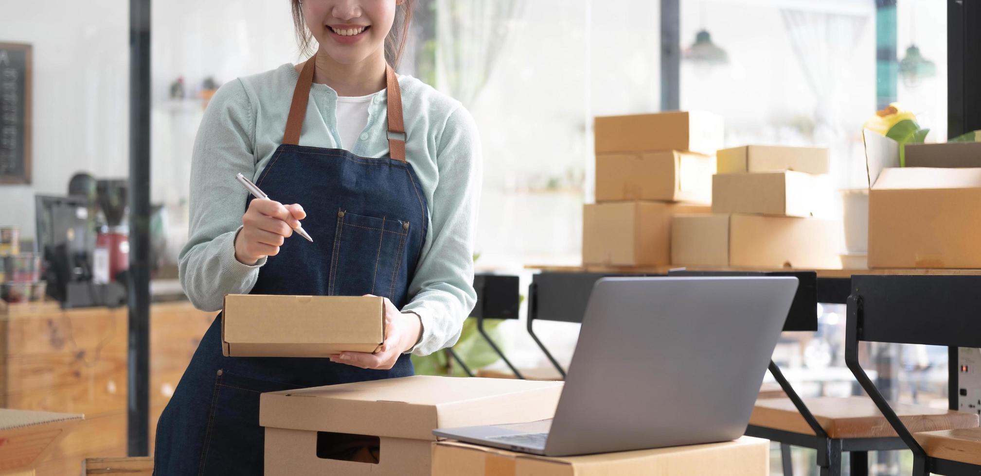 Envío de compras en línea, joven emprendedor de pequeña empresa escribiendo la dirección en una caja de cartón en el lugar de trabajo. foto