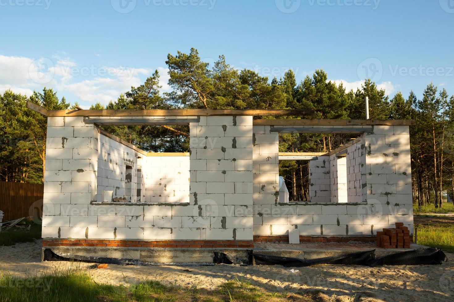 The object of unfinished construction is a future house made of a porous concrete block. 1st floor with an attic. Housing in rural areas is under construction. Walls with windows photo