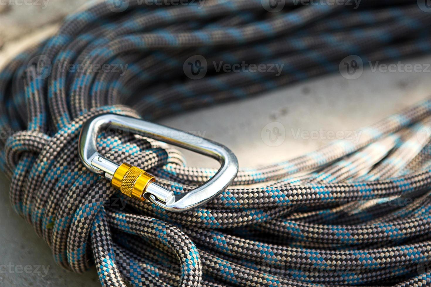Coiled climbing rope and steel carabiner. Mountain climbing equipment harness, brakes, quickdraws, self-insurance, belay device eight. On a stone background with cracks. Flatlay, copy space photo