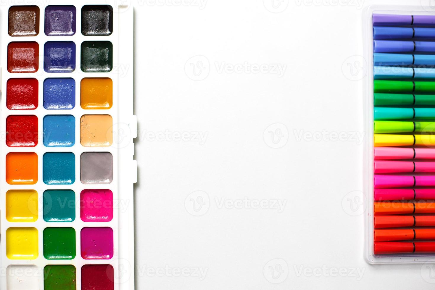 A palette of color watercolors with brushes and markers on a white background with space for text. photo