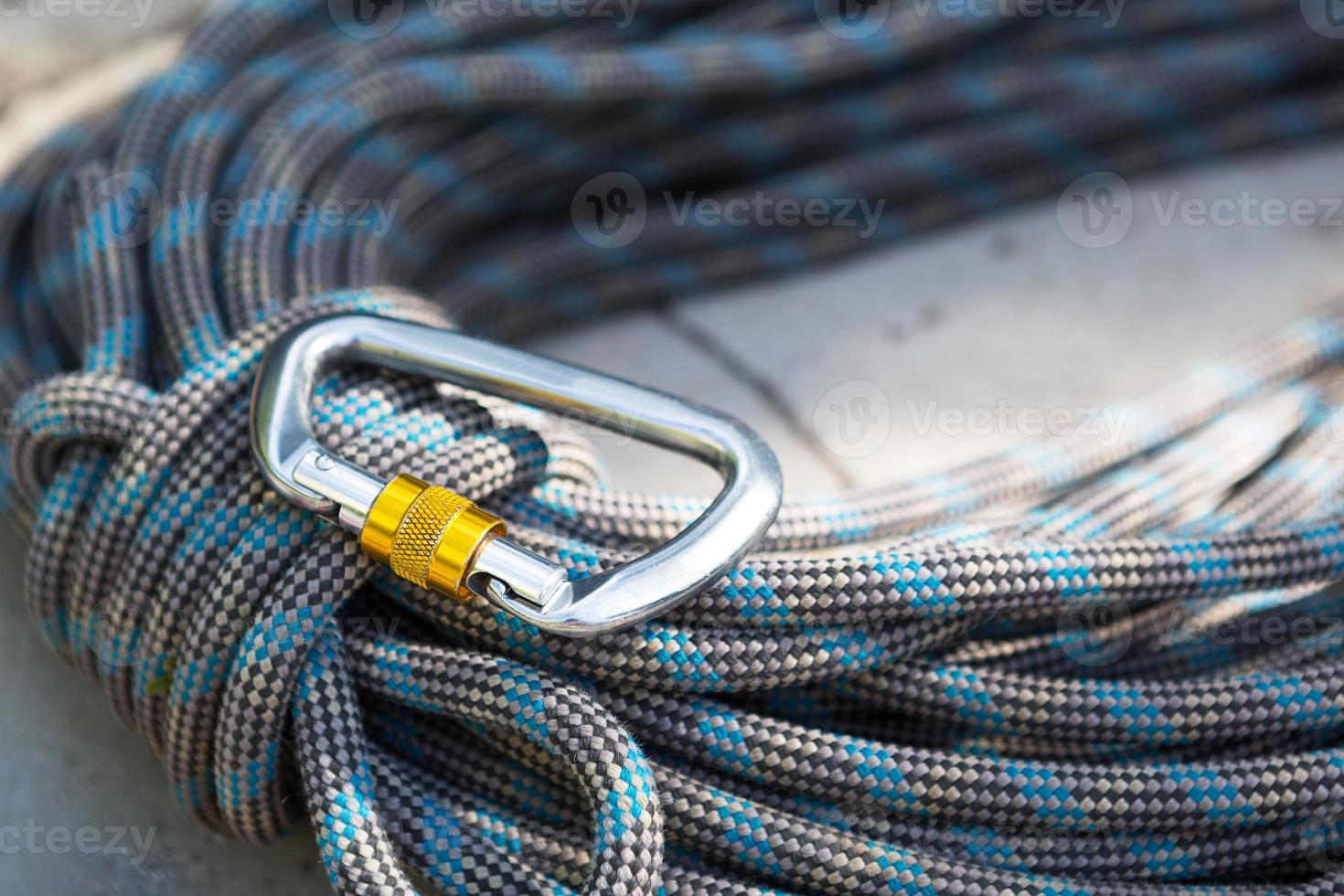 Coiled climbing rope and steel carabiner. Mountain climbing equipment harness, brakes, quickdraws, self-insurance, belay device eight. On a stone background with cracks. Flatlay, copy space photo