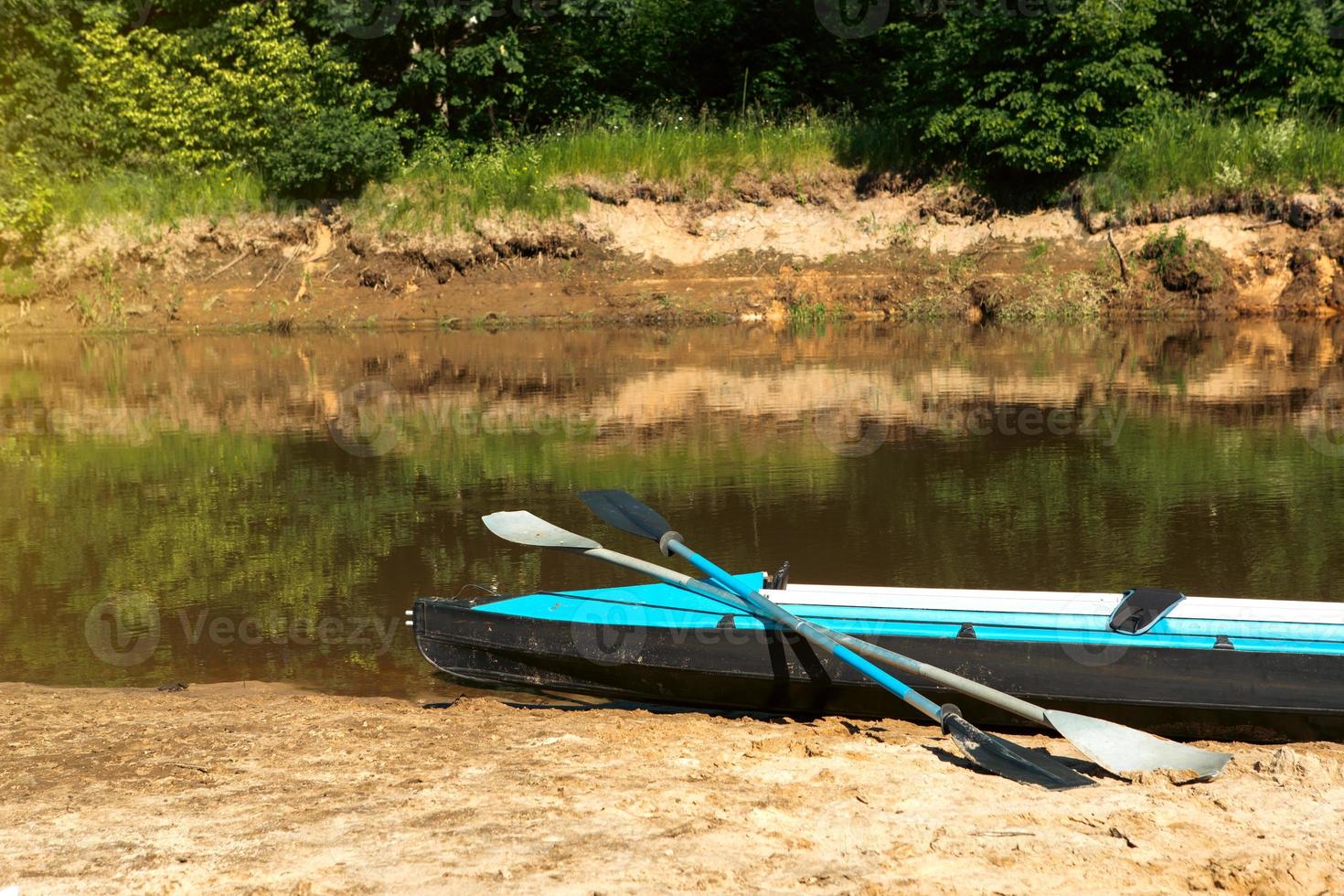 Tourist canoes with paddles stand on the river coast in summer on a water hike. Rafting on inflatable and frame double and triple kayak boats, family trip, extreme adventure in summer photo