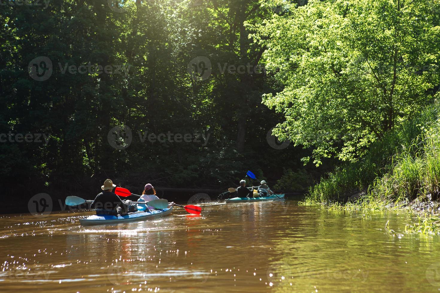 Family kayak trip. Man and woman and elderly couple senior and seniora rowing boat on the river, a water hike, a summer adventure. Eco-friendly and extreme tourism, active and healthy lifestyle photo