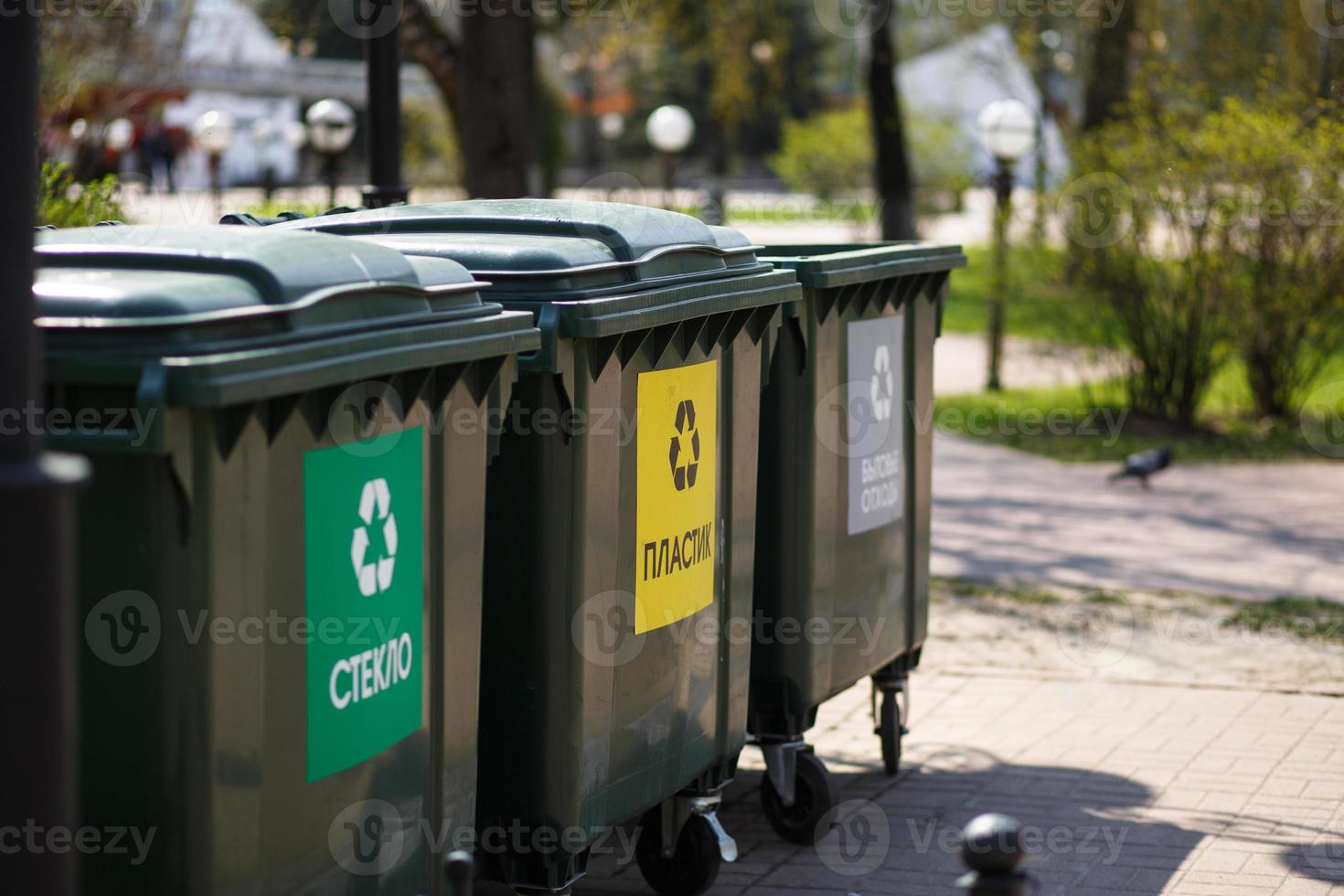 Hand with a bag of plastic garbage over containers for separation and sorting in Russia with the words Glass, plastic, household waste. photo