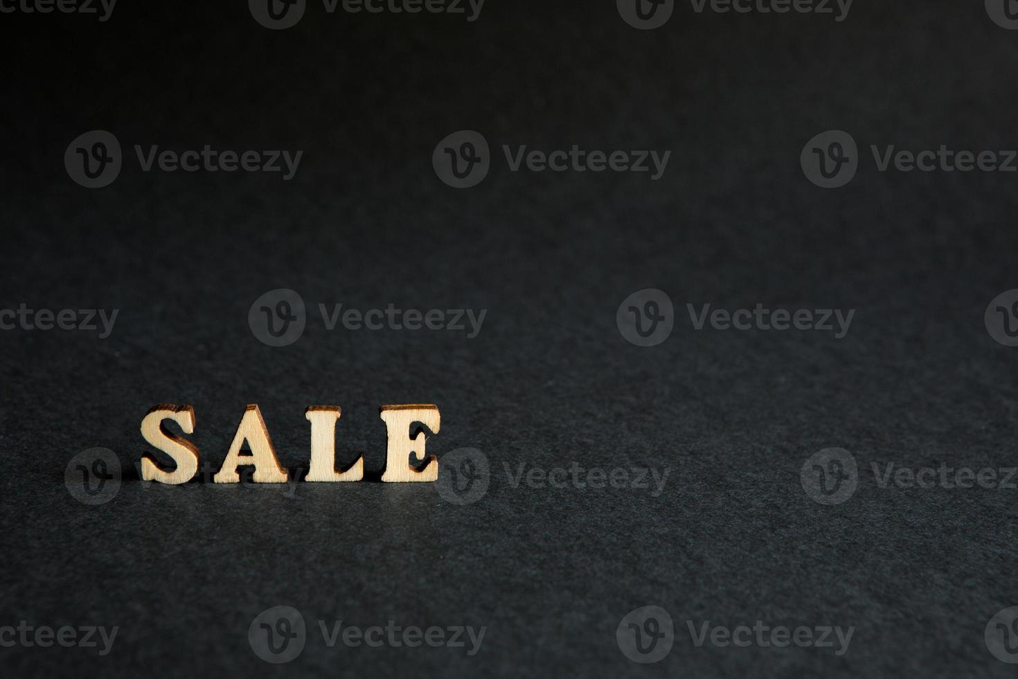 inscription Sale of wooden letters on a black background. Black Friday, discounts, sale, shopping, interest sign. Space for text photo