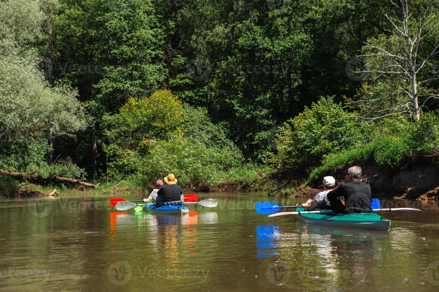 Family kayak trip. Man and woman and elderly couple senior and seniora rowing boat on the river, a water hike, a summer adventure. Eco-friendly and extreme tourism, active and healthy lifestyle photo