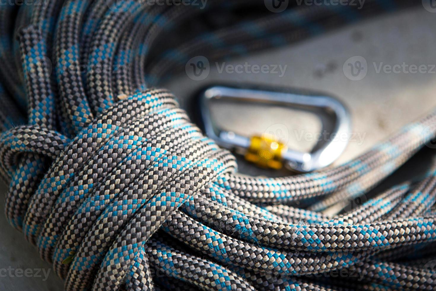 Coiled climbing rope and steel carabiner. Mountain climbing equipment harness, brakes, quickdraws, self-insurance, belay device eight. On a stone background with cracks. Flatlay, copy space photo
