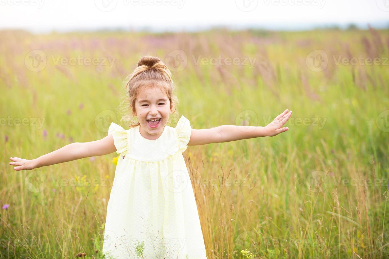 The girl runs into the field with her arms outstretched like an airplane. Carefree childhood, summer freedom, travel. International Children Day. Mosquito repellent, cottage core. photo