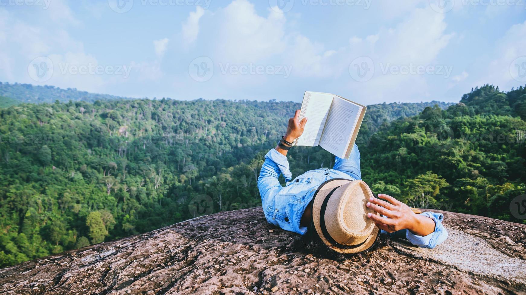 el hombre asiático viaja relájese en las vacaciones. dormir relajarse leer libros sobre acantilados rocosos. en la montaña de verano foto