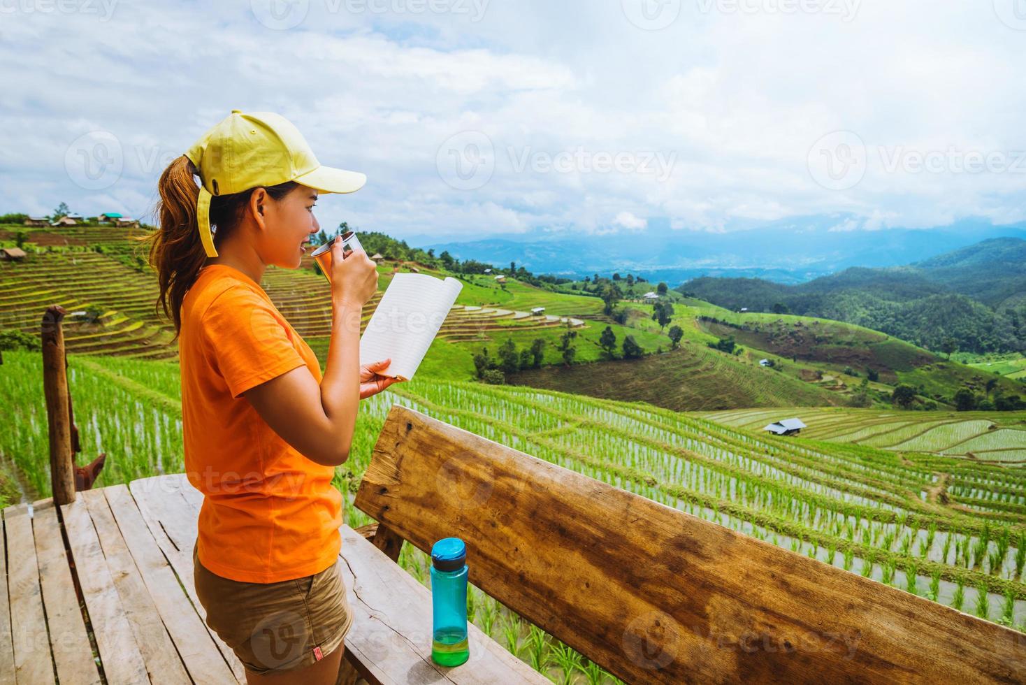 naturaleza de viaje de mujer asiática. viajar relajarse. de pie leyendo un libro en el balcón de la casa. en verano. foto