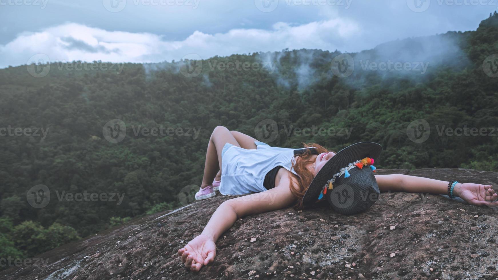 Asian woman travel nature. Travel relax. Freedom happy traveler woman standing with raised arms and enjoying a beautiful nature on peak of foggy mountain. photo