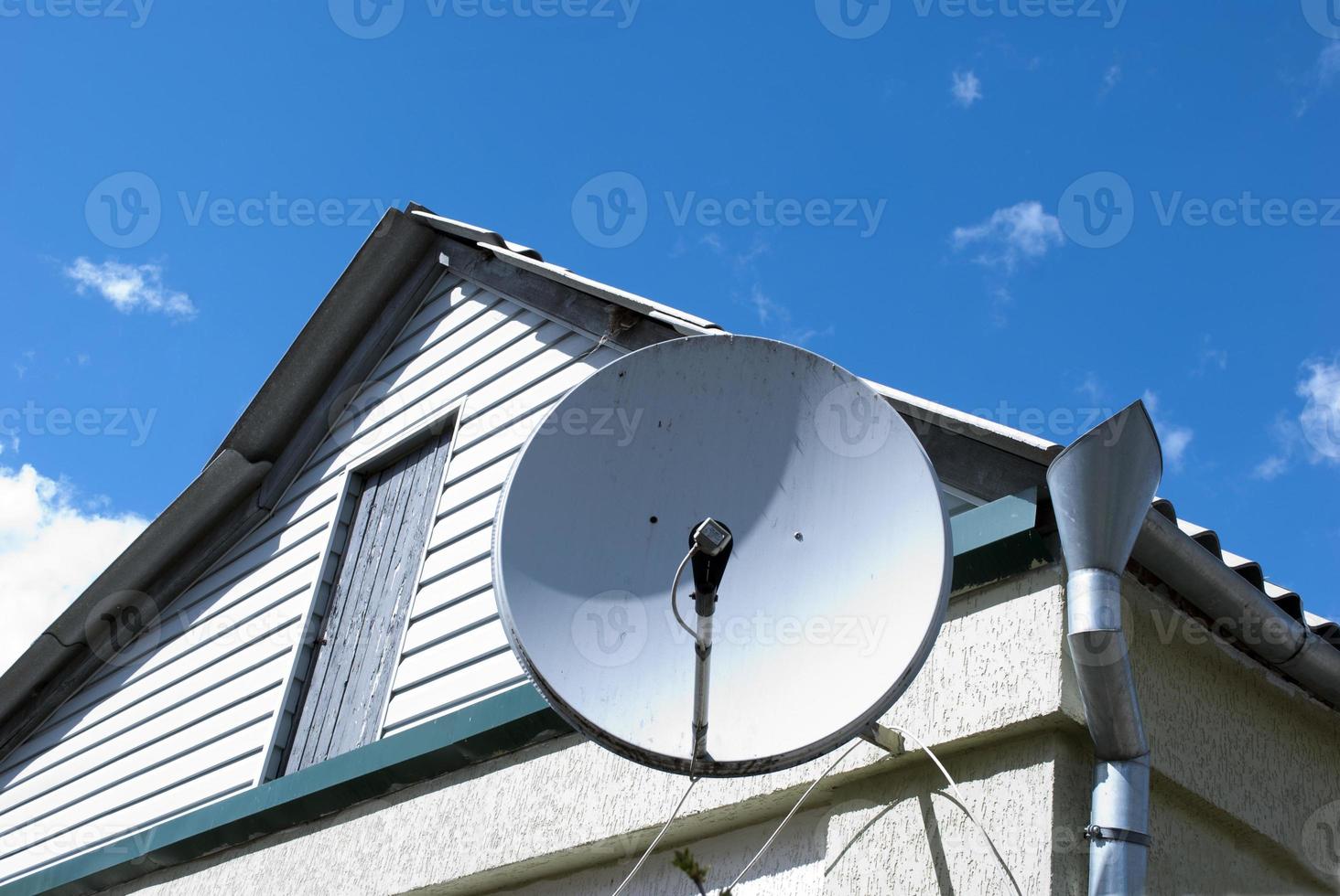 antena parabólica en la pared nubes en el cielo tiempo solar foto