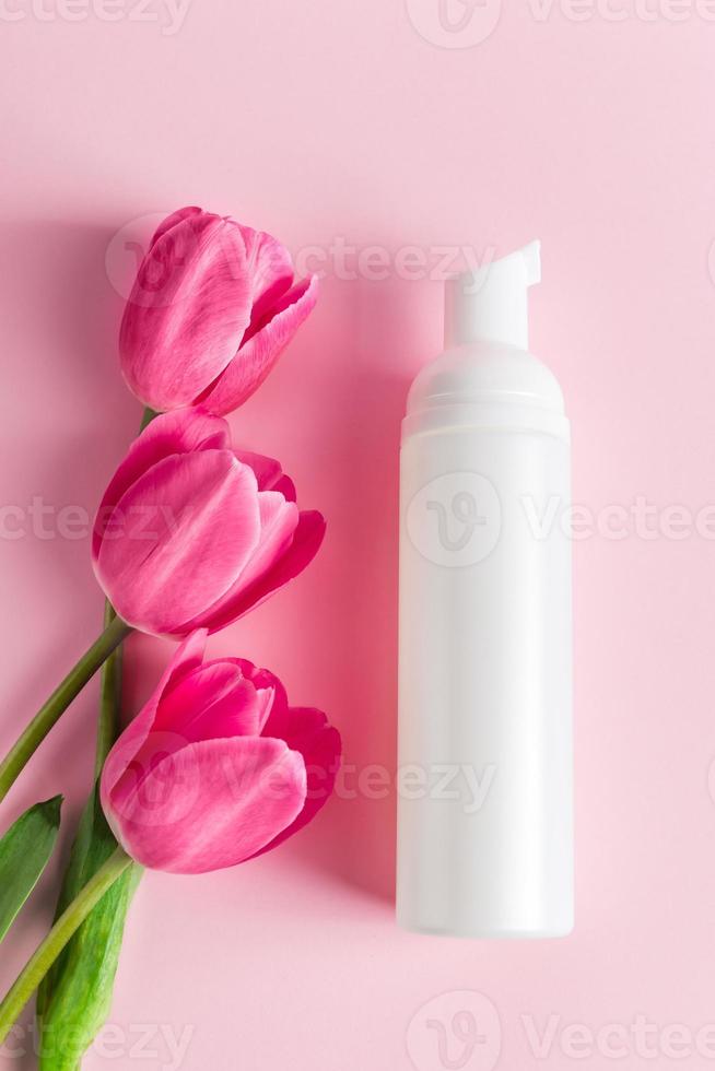 Spa skin care products on a pink background. Natural cosmetics and red tulips. photo