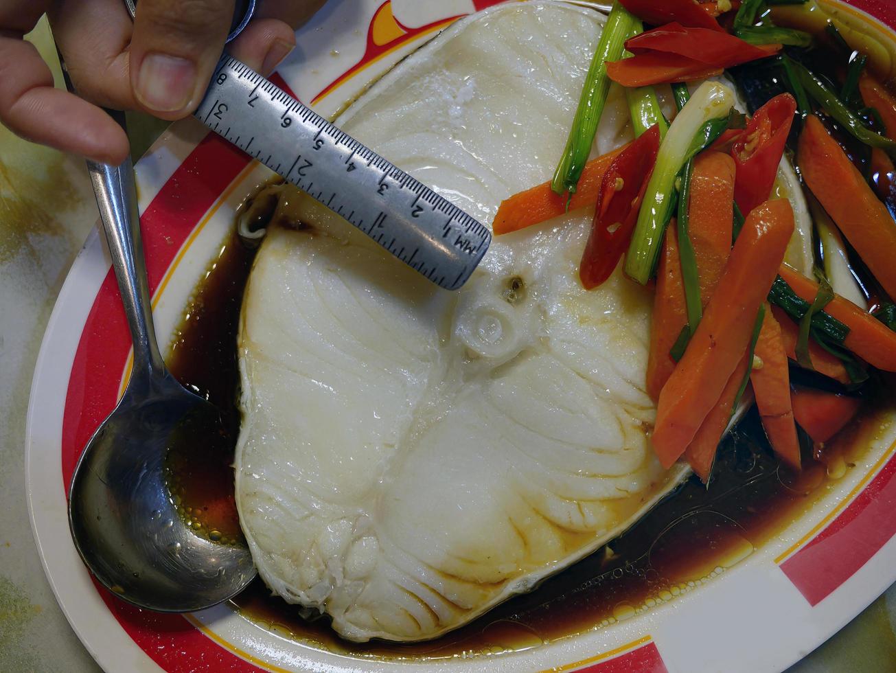 Enjoy meal measure size of steamed Chilean Seabass fish in soy sauce dish photo