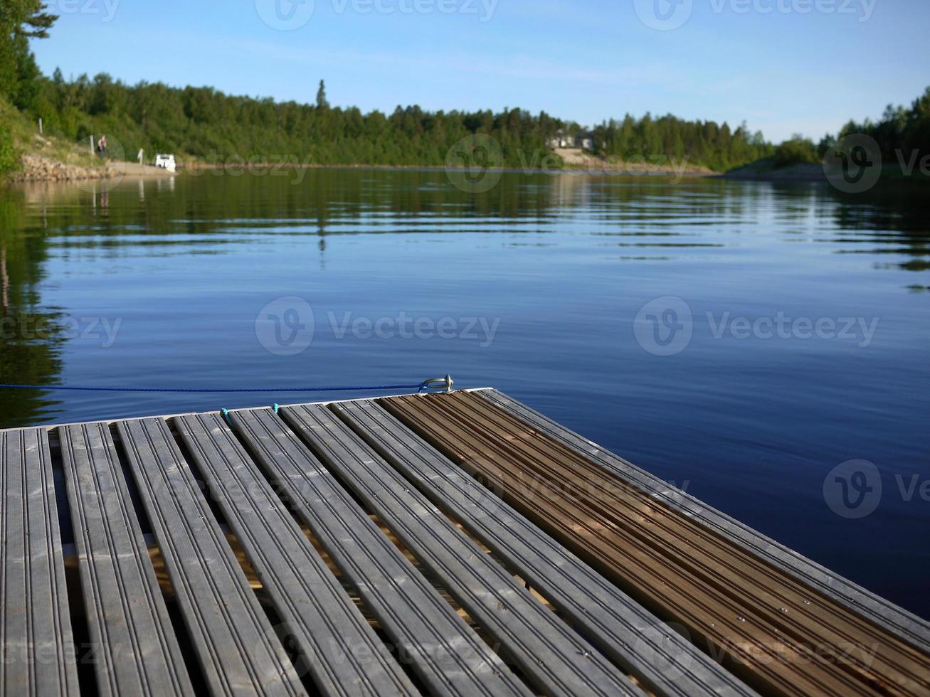 Wooden dock in ivalo clear river at midnight time finland scandinavia photo