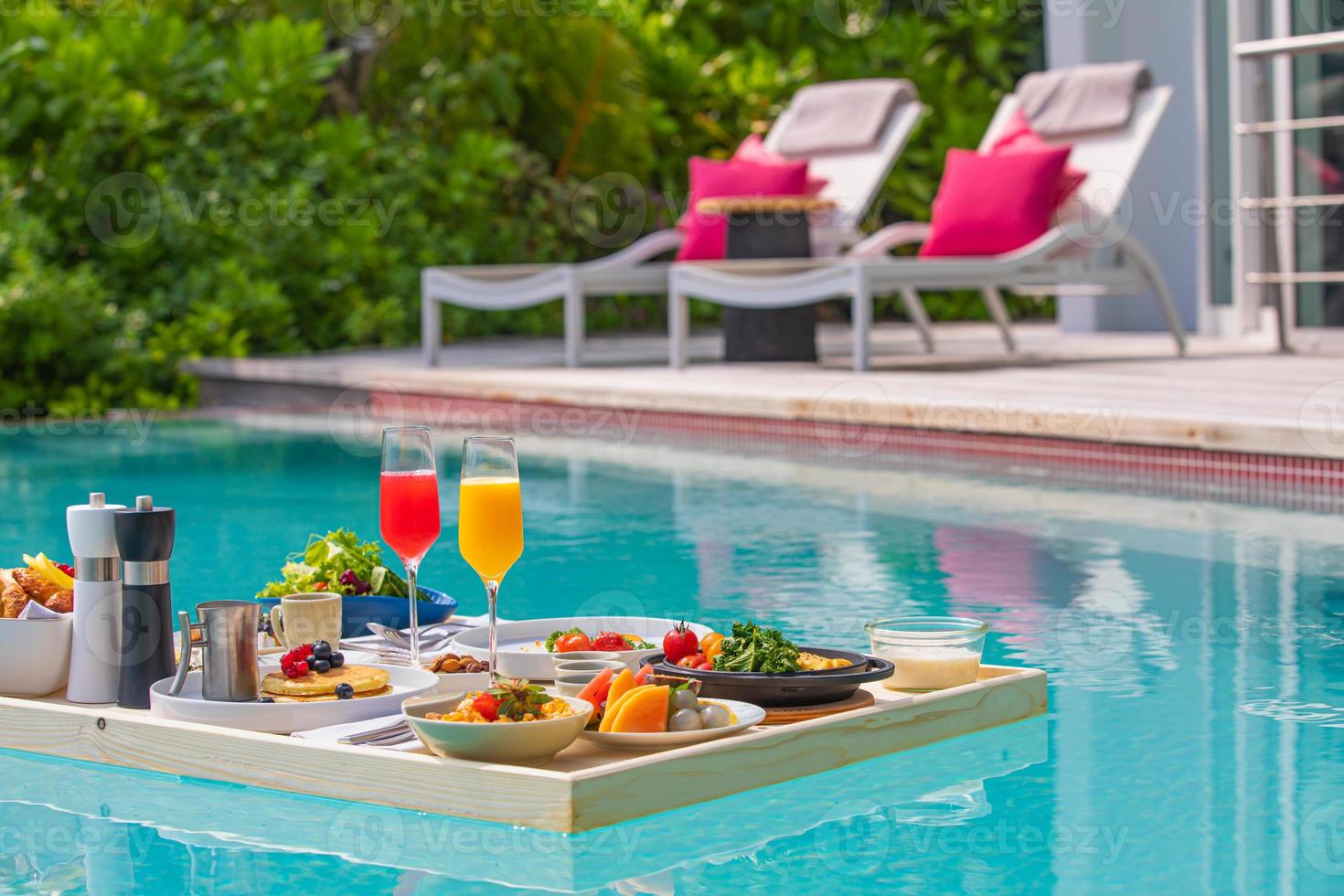 desayuno en piscina, desayuno flotante en resort tropical. mesa relajante en aguas tranquilas de la piscina, desayuno saludable y plato de frutas junto a la piscina del complejo. dieta exótica de verano. estilo de vida de playa tropical foto