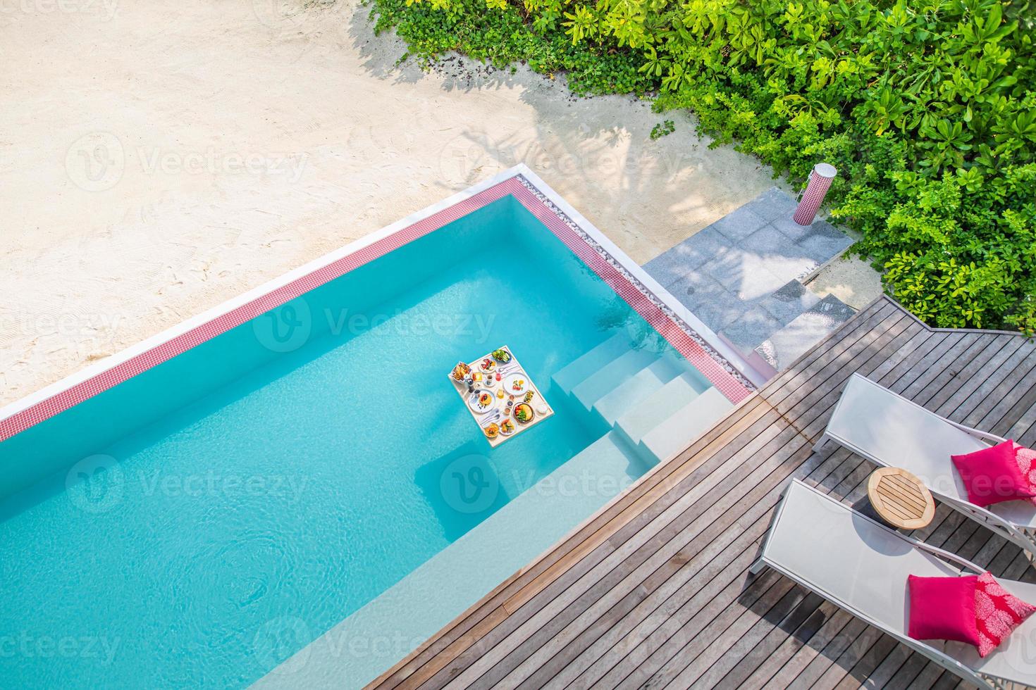 Breakfast in swimming pool, floating breakfast in tropical resort. Table relaxing in calm pool water, healthy breakfast and fruit plate by resort pool. Exotic summer diet. Tropical beach lifestyle photo