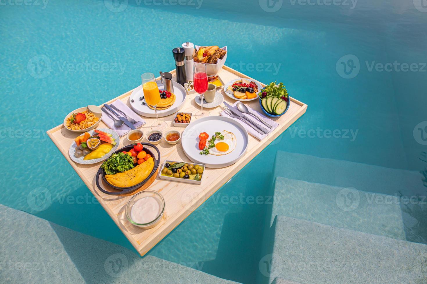 Breakfast in swimming pool, floating breakfast in tropical resort. Table relaxing in calm pool water, healthy breakfast and fruit plate by resort pool. Exotic summer diet. Tropical beach lifestyle photo