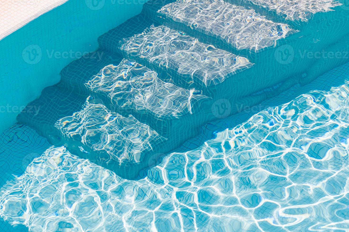 Pool steps underwater. Stairs in swimming pool with turquoise water at sunny day. photo