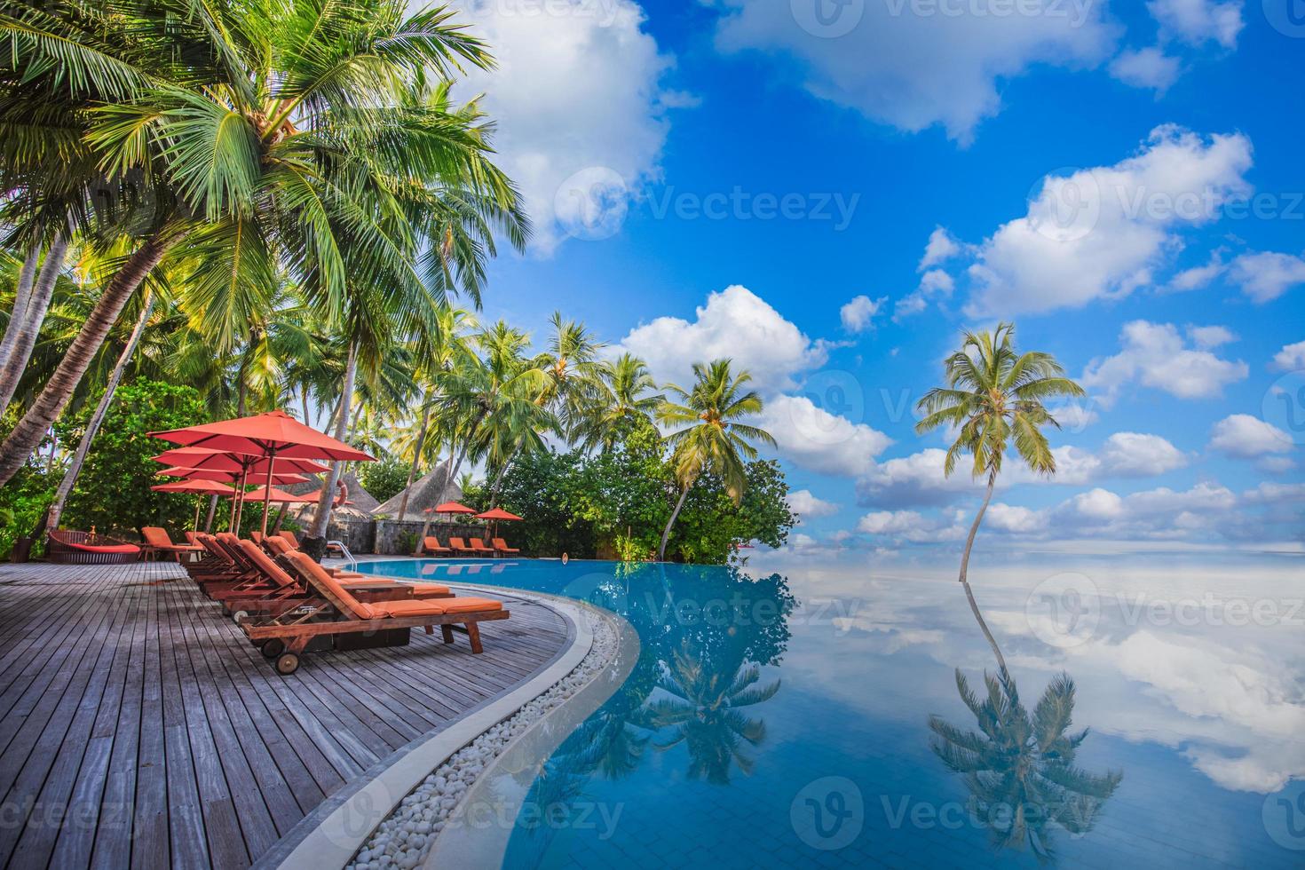Panoramic holiday landscape. Luxurious beach resort hotel swimming pool and beach chairs or loungers under umbrellas with palm trees, blue sunny sky. Summer island seaside, travel vacation background photo