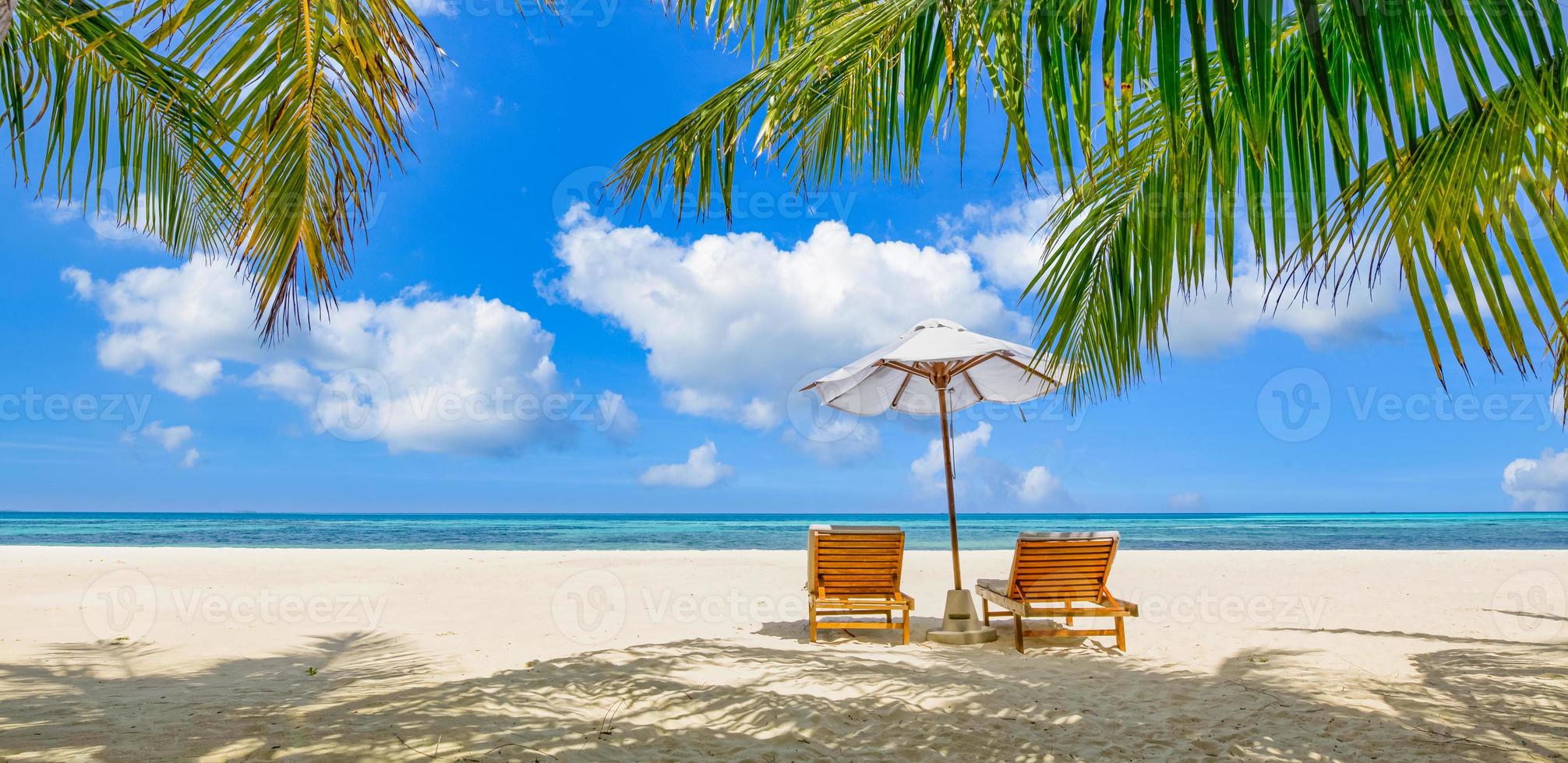 Beautiful tropical island scenery, two sun beds, loungers, umbrella under palm tree. White sand, sea view with horizon, idyllic blue sky, calmness and relaxation. Inspirational beach resort hotel photo