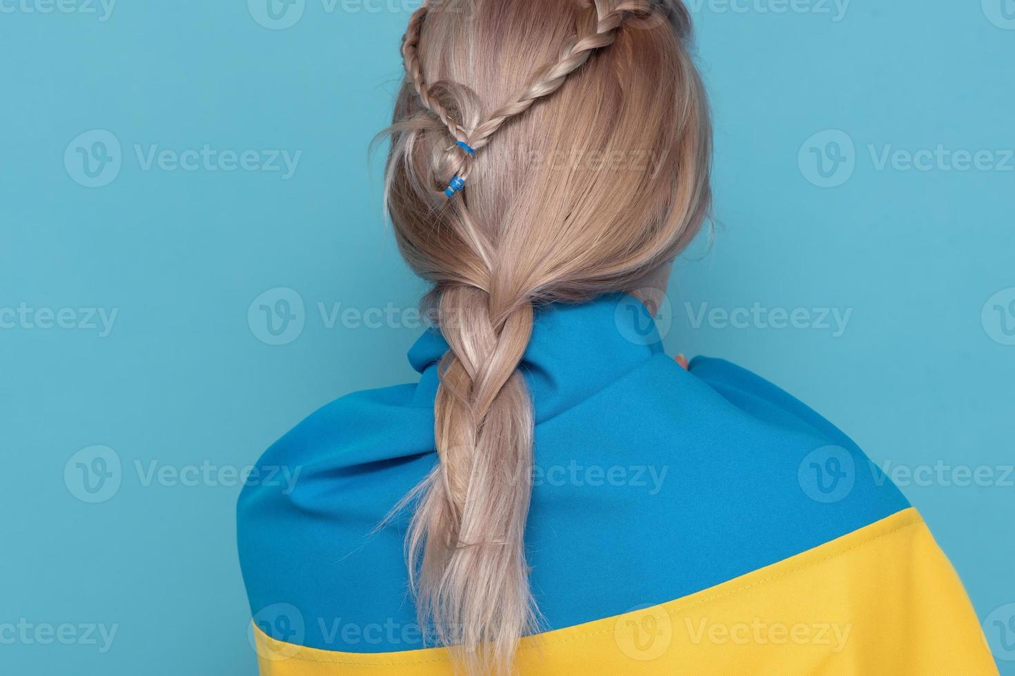 Woman with blue-yellow cloth on her shoulders. Woman back to camera on a blue background. photo