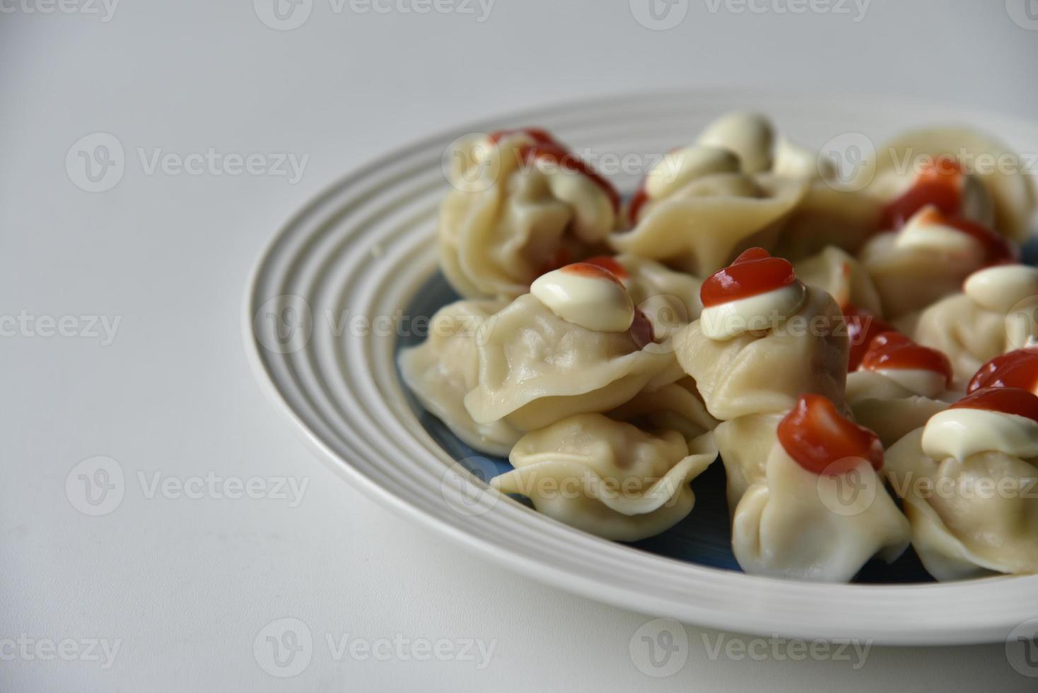 Cooked dumplings on a plate with ketchup and mayonnaise photo