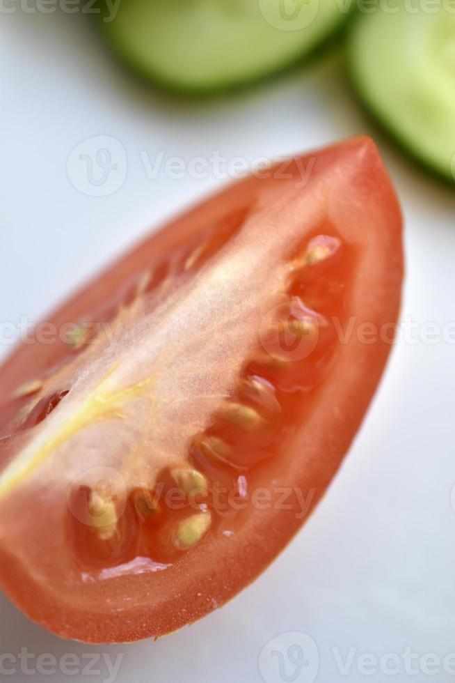 Sliced red tomatoes and green cucumber close-up on a plate photo