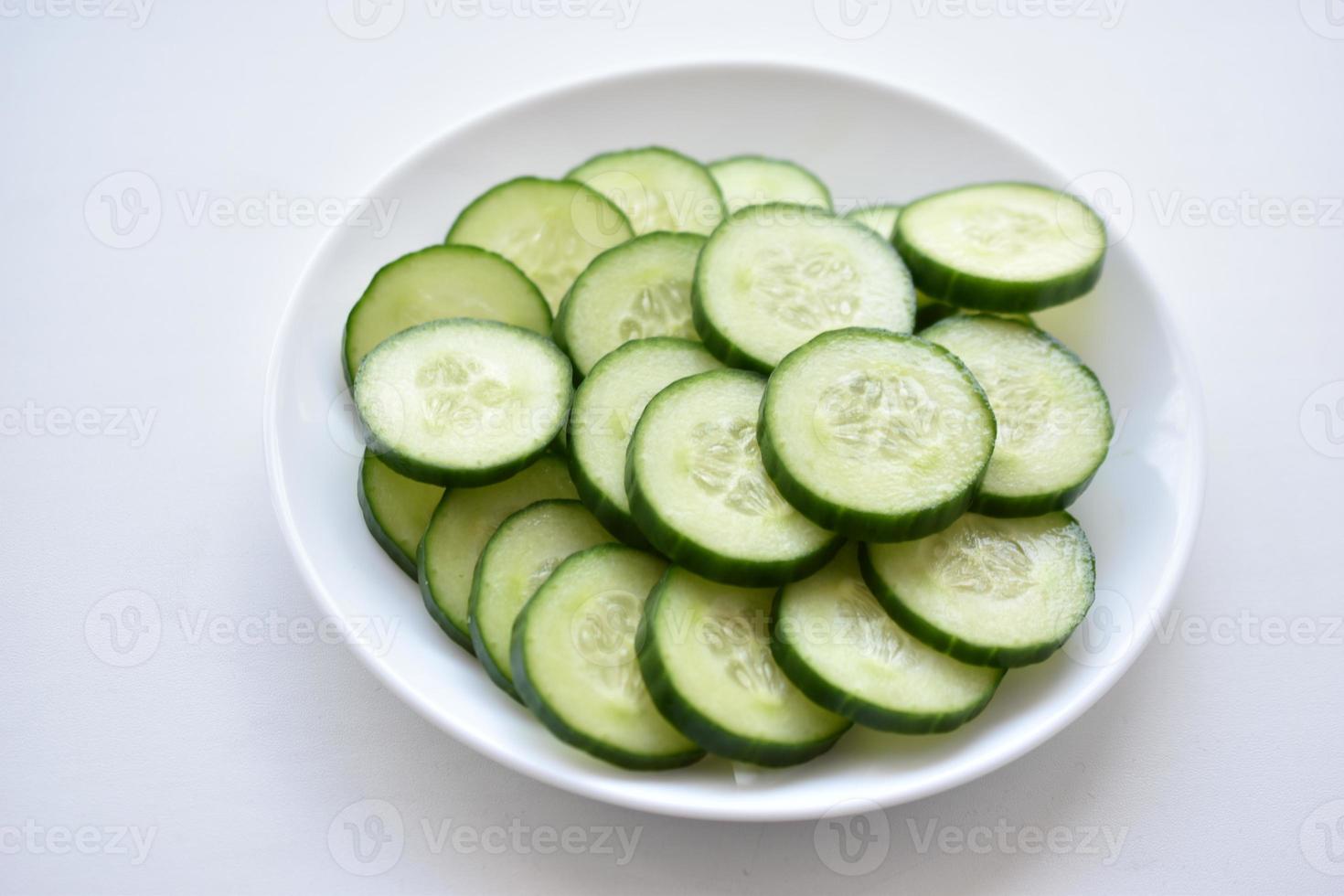 Sliced cucumber slices on a white plate with a fork photo