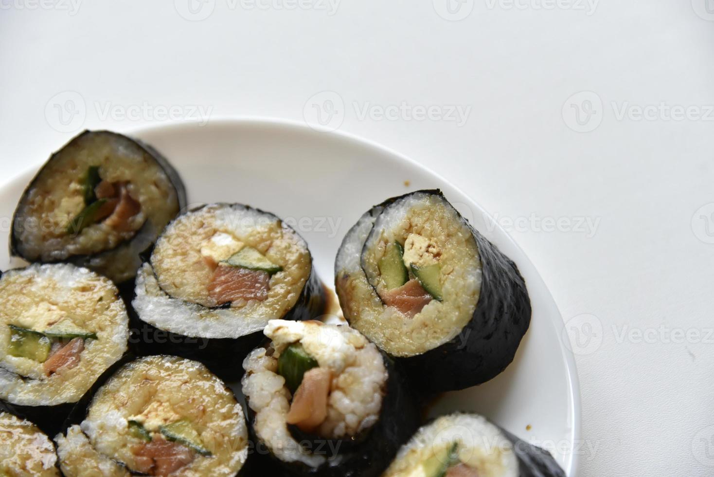 rollos de arroz con salmón y queso en un plato blanco. sushi japonés foto