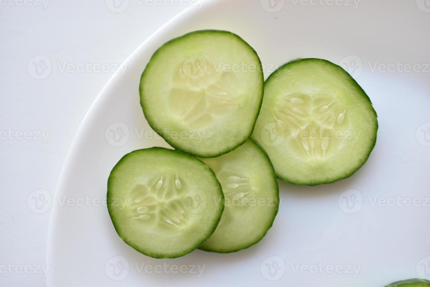 Sliced cucumber slices on a white plate with a fork photo