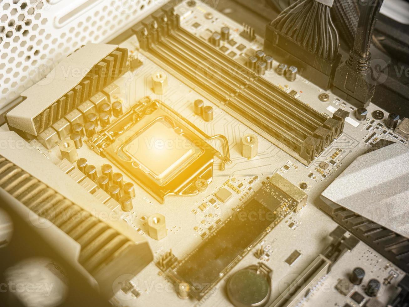 Hold the CPU handle and insert it into the CPU slot on the motherboard. It's an old motherboard, lots of dust. Put orange light on the cpu slot. There is a RAM slot next to it. There is a capacitor. photo