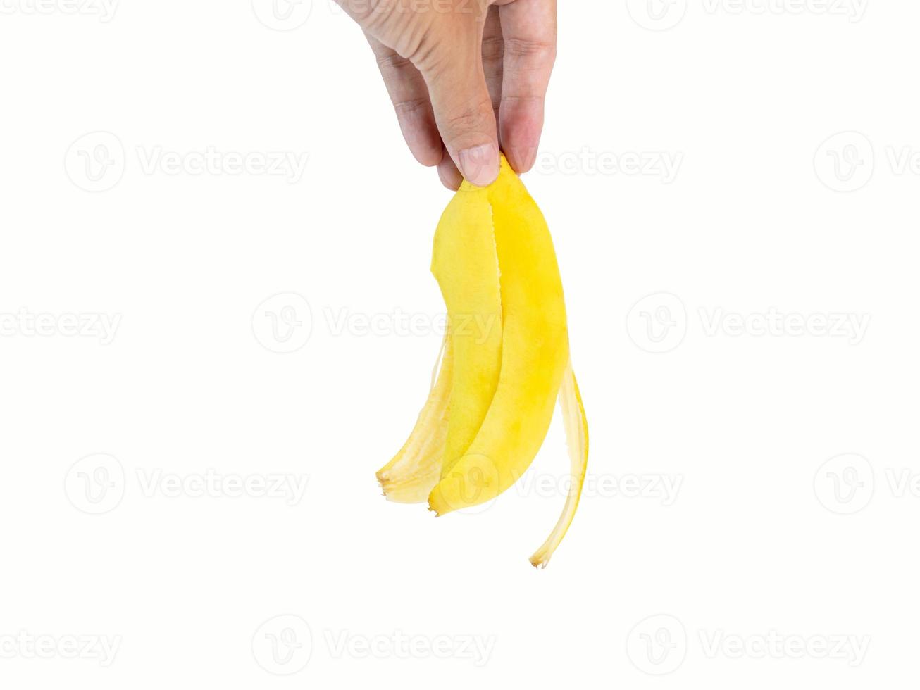 mano que sostiene una cáscara de plátano, una fruta de color amarillo dorado que se ha comido hasta el final, dejando solo la cáscara. filmado en el estudio sobre un fondo blanco con trazados de recorte y espacio de copia aislado. foto