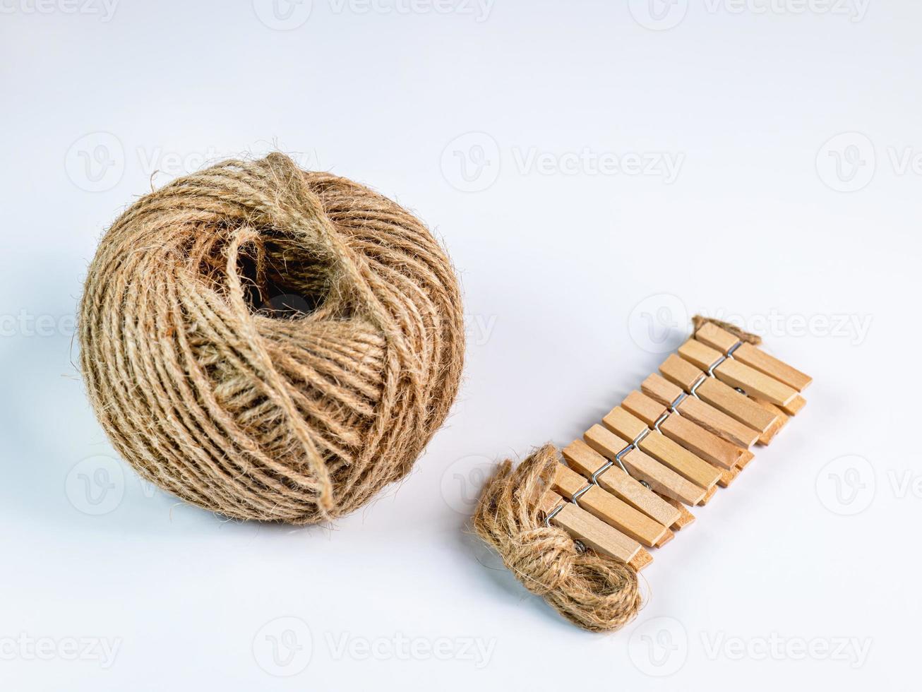 coiled raw rope Made of various fibers into a long rope. Empty with a small clip made of wood. For brown crafts, white background isolated, studio shot. photo
