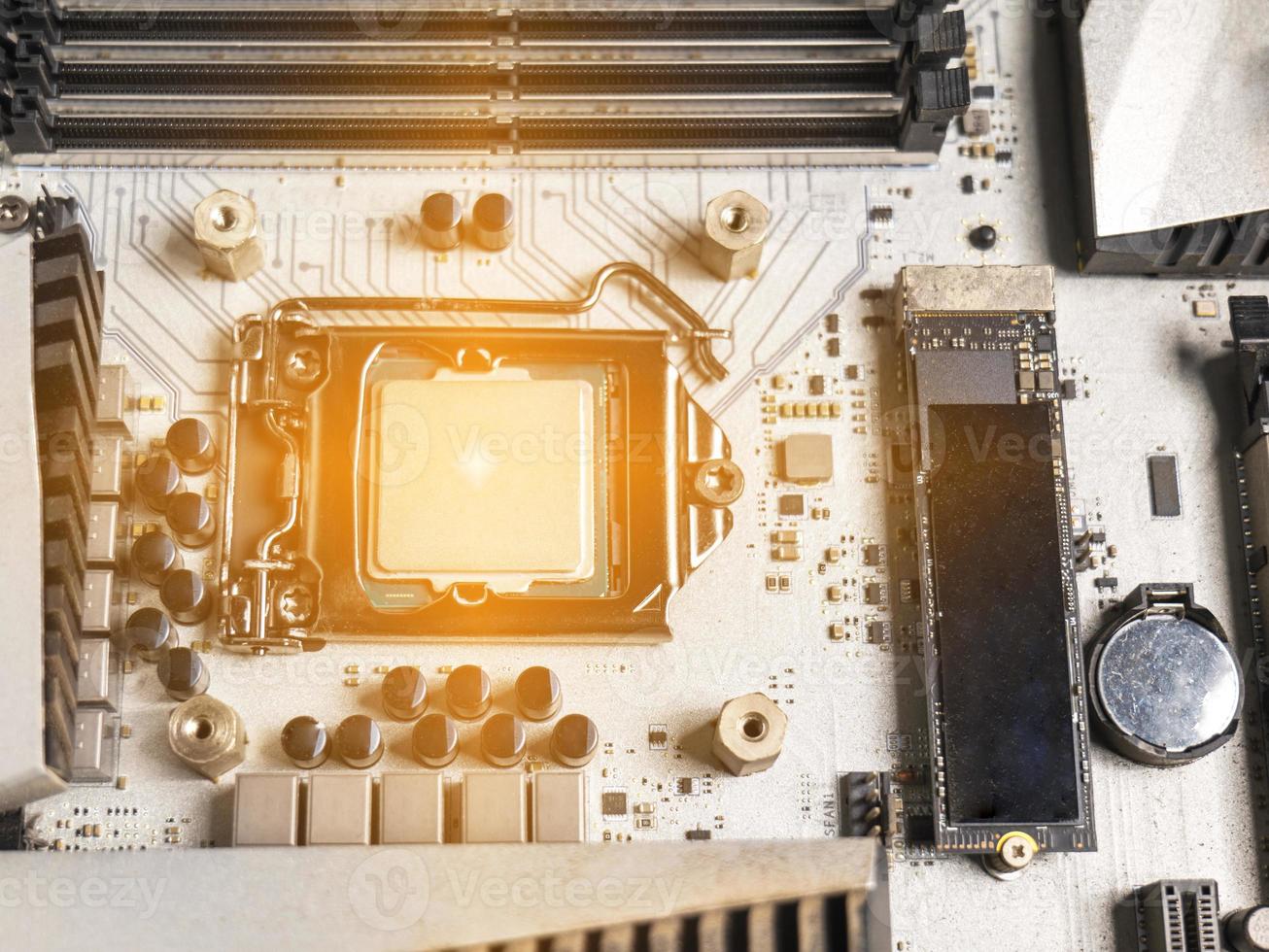 Hold the CPU handle and insert it into the CPU slot on the motherboard. It's an old motherboard, lots of dust. Put orange light on the cpu slot. There is a RAM slot next to it. There is a capacitor. photo