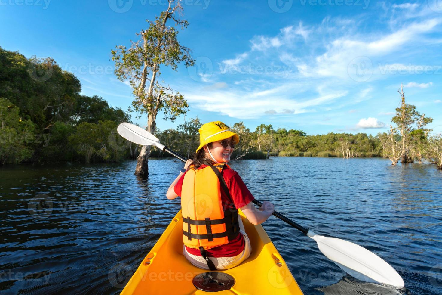 happy woman kayaking with kayak boat in nuture lake behind sea and beach before sunset time for relax and extreme water sport photo