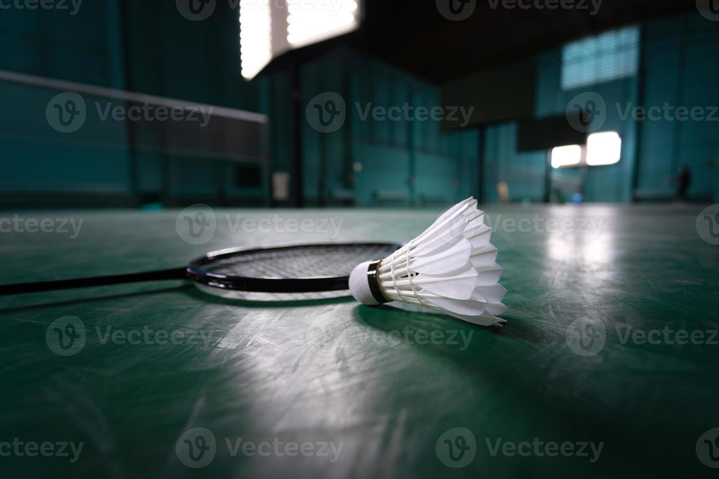 pelota de bádminton o gallo de lanzadera con raqueta de bádminton en la cancha con jugador profesional de bádminton jugar en la cancha en el gimnasio para una competencia de campeonato saludable y deportiva foto