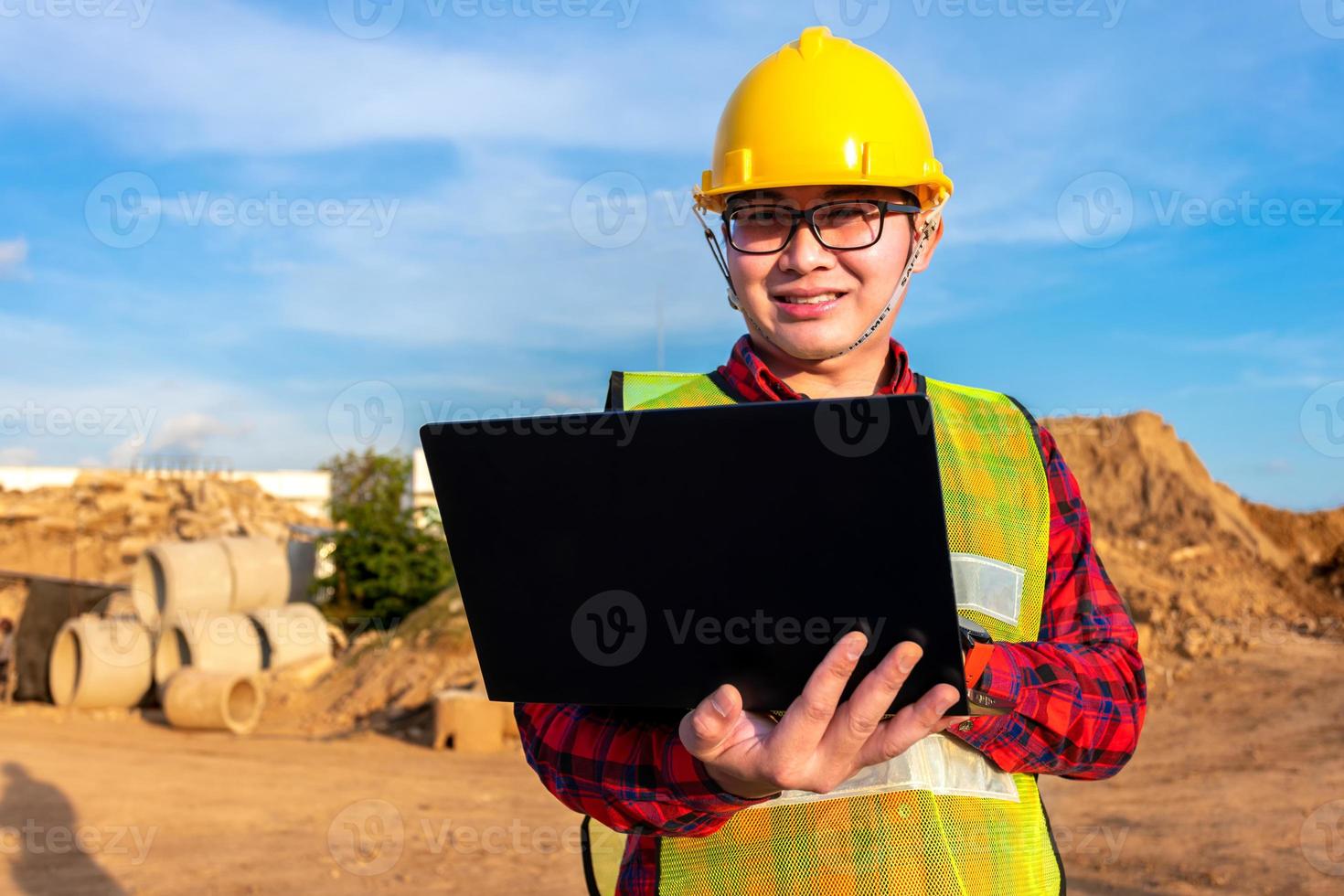 el ingeniero civil técnico asiático usa una tableta con tecnología de pluma inteligente en la construcción del sitio de transporte para inspeccionar el trabajo de ingeniería de planos en línea con el equipo al atardecer foto