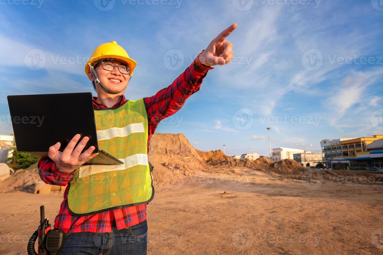 asian technician civil engineer use tablet with smart pen technology on transport site construction to inspect blueprint engineering work online with team at sunset time photo