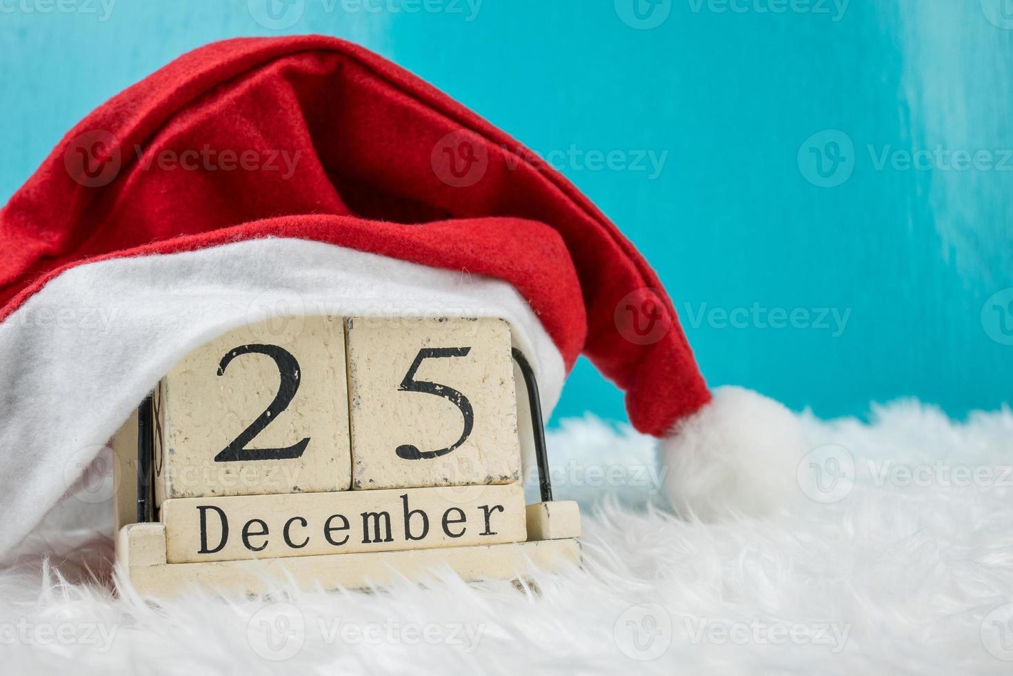 tema del día de navidad y decoración con sombrero santa.calendario de bloque de cubo de madera fecha actual 25 y mes de diciembre.copiar espacio para texto.celebración navidad y x'mas concept.sobre fondo verde foto