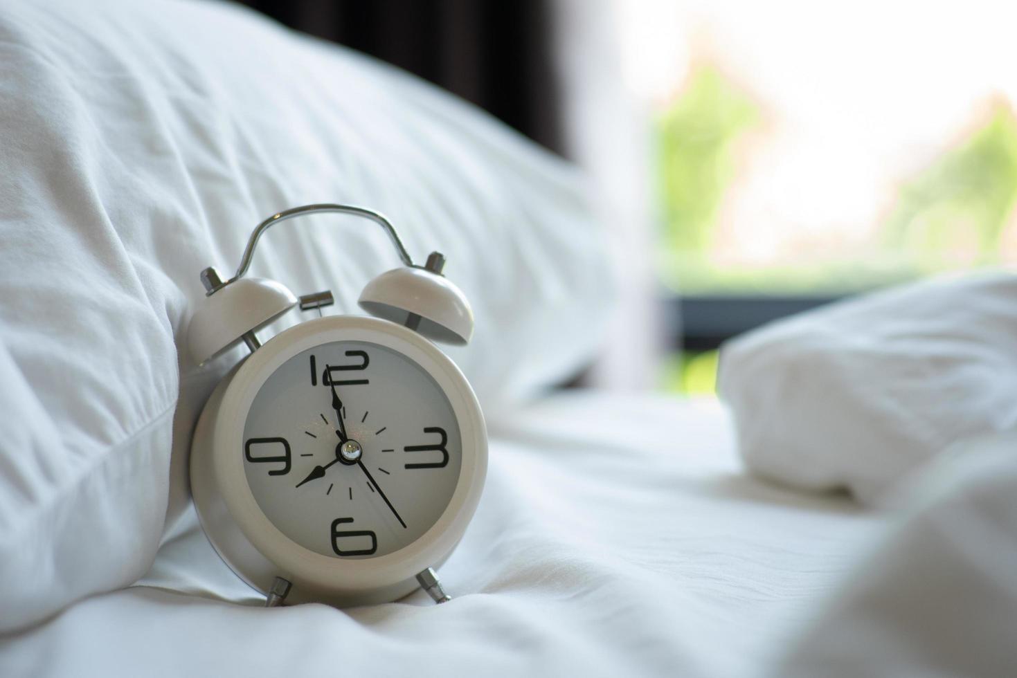 Retro white alarm clock On the white mattress in the bedroom photo