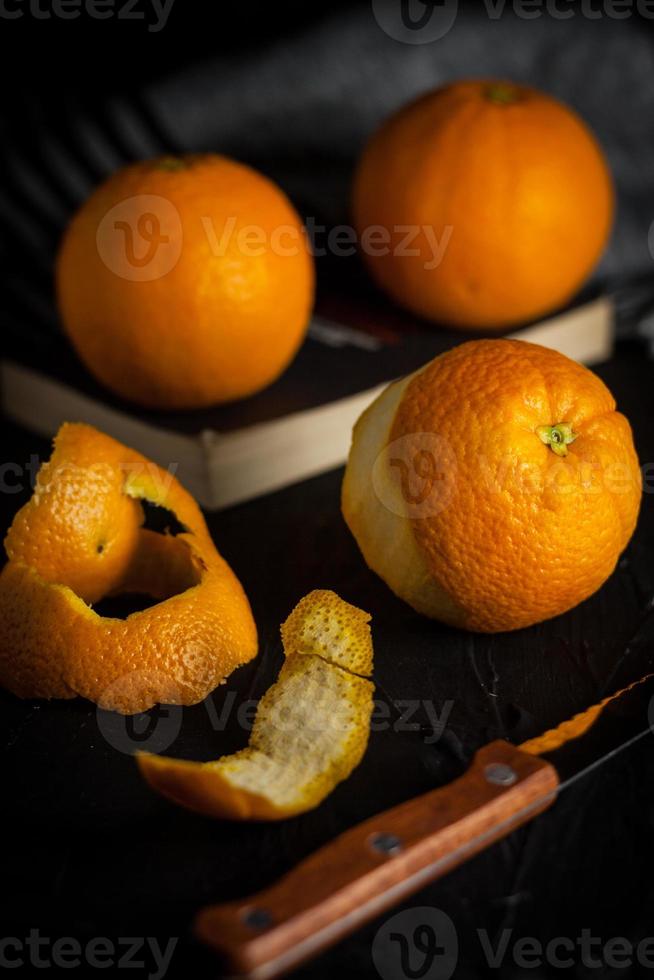 spanish oranges freshly on book and peels oranges before eating on black background,angle view photo
