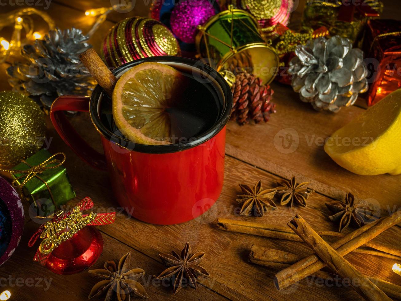 Hot drink alcohol,Mulled red wine in red rustic mugs spices cinnamon stick and citrus fruit.decoratied fir festive on wood table.Celebration christmas and Happy New Year Concept. photo