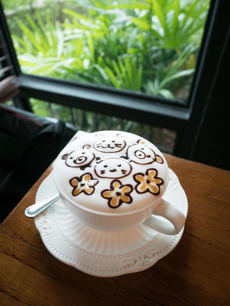 Cappuccino with fresh milk foam and latte art in a white ceramic glass on a wooden table at a coffee shop. photo